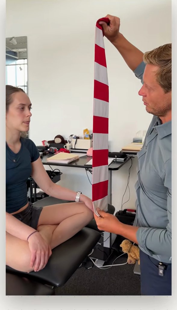 Clinician holding a red and white striped cloth vertically in front of a seated patient to test eye tracking